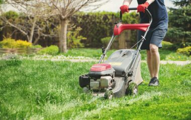 Man cutting the grass with loan mover.